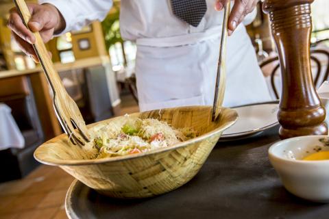 Close up of a chef tossing a salad in a wooden bowl with wooden utensils at Columbia Restaurant