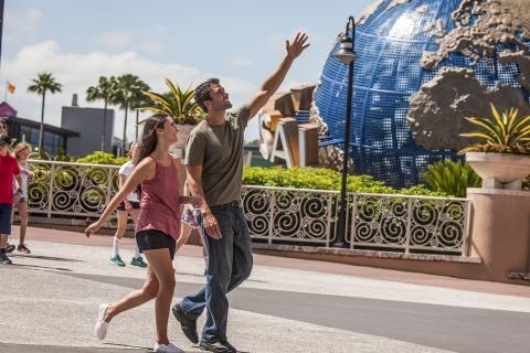 Couple walking and smiling near the iconic Universal globe at Universal Orlando Resort on a sunny day in Central Florida.