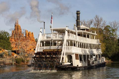 White steamboat floating down river at Magic Kingdom Park.
