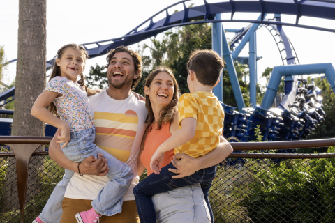 Family of four laugh in front of Manta at SeaWorld Orlando.