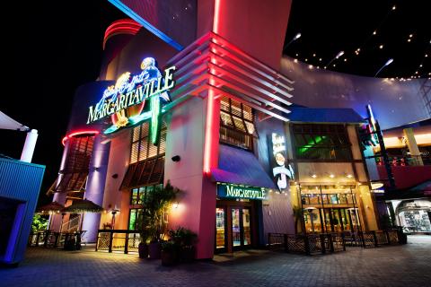 Jimmy Buffett’s Margaritaville at Universal CityWalk glows at night, with colorful neon signs, palm accents, and outdoor seating lighting up the walkway.