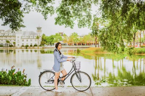 Girl biking along the water on the sidewalk in downtown celebration