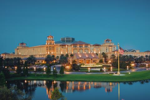 Beautiful exterior of Gaylord Palms Resort at dusk with clear reflection in the water below.