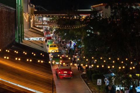 Night photo of classic cars driving down brick road at Old Town Kissimmee. 