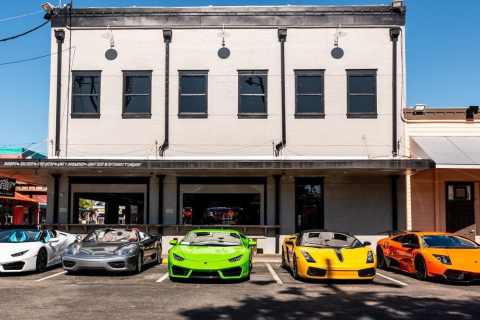 White, blue, lime green, yellow, and orange cars parked in front of a white building at Old Town Kissimmee.