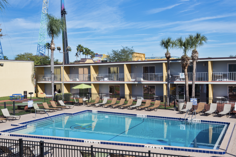 Blue outdoor pool surrounded by lounge chairs and hotel rooms at Celebration Suites.