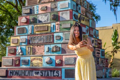Girl in yellow dress takes photo in front of Monument of States in Downtown Kissimmee.