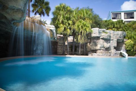 Blue pool with waterfall and palm trees at Delta Hotels by Marriott Orlando Celebration