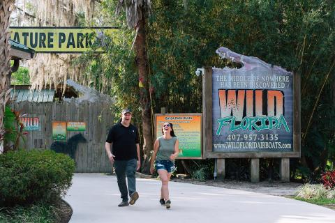 Jeff Musial and Jen Bonner walk down the entrance walkway at Wild Florida with trees in the background.
