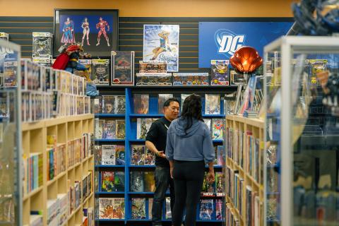 Ming Chen and Jen Bonner stand at the end of an aisle of colorful comic books