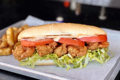 Fried shrimp with lettuce and tomato in a sub-sandwich bun on a white plate at Island Cloud Grill.