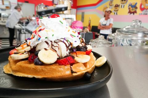 Stack of waffles with bananas and strawberries topped with whip cream at Pops Waffle & Ice Cream Shoppe in Downtown St. Cloud