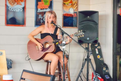 Musician performing live acoustic guitar and vocals at Crabby Bill’s in St. Cloud, Florida, with colorful seafood-themed posters in the background.