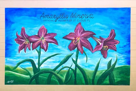 Colorful mural depicting the Amaryllis Minerva, the official flower of St. Cloud, Florida, with vibrant pink blooms against a bright blue sky and green hills.