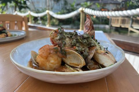 Seafood stew at MOOR, featuring shrimp, clams, and toasted bread in a rich broth, served waterside at Gaylord Palms.