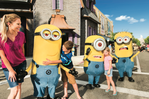 Children hug and interact with three Minion characters at Universal Orlando Resort. 