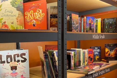 Shelves of colorful children’s and middle-grade books displayed in a bookstore, including illustrated poetry, graphic novels, and fiction titles arranged neatly under labeled sections.