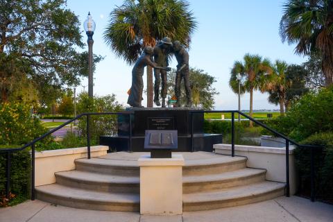 Bataan-Corregidor Memorial in Kissimmee, Florida, featuring a statue of soldiers and a nurse on a raised platform at Lakefront Park.