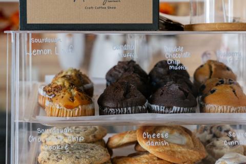 Display case filled with fresh pastries, including muffins, cookies, and bagels, at Madilynn’s Craft Coffee Shop in St. Cloud, Florida.