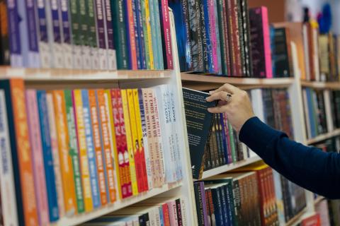 A person pulls a book out of a shelf.