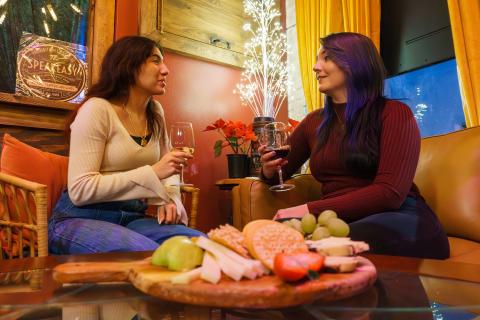 Two women enjoying wine and a gourmet cheese board in the cozy atmosphere of Vintage Vino, Downtown Kissimmee's wine bar.