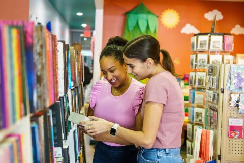 Two women smile as they browse through books inside a White Rose Books & More in Downtown Kissimmee.