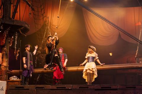 Chelsea Green swings from a rope onstage at Pirates Dinner Adventure in Kissimmee, dressed in a pirate costume.