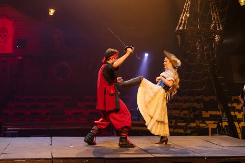 Jen Bonner, dressed as a pirate, performs a high kick alongside a pirate performer during a stage stunt at Pirates Dinner Adventure.