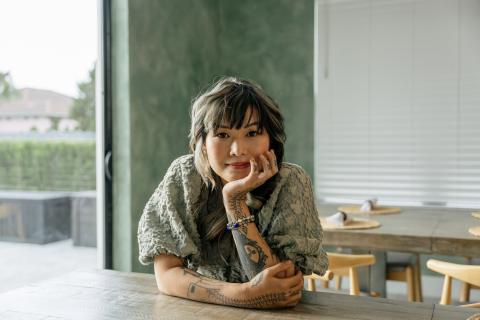 Yvette Young rests her face in her hand, gazing thoughtfully at the camera inside a stylish Kissimmee vacation home.