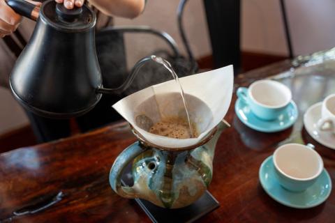 Hot water being poured into a ceramic vandola over freshly ground coffee, part of the slow-brew process unique to Susana’s Café.