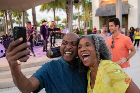Couple taking a selfie in front of a live band at Promenade at Sunset Walk in Kissimmee, Florida.
