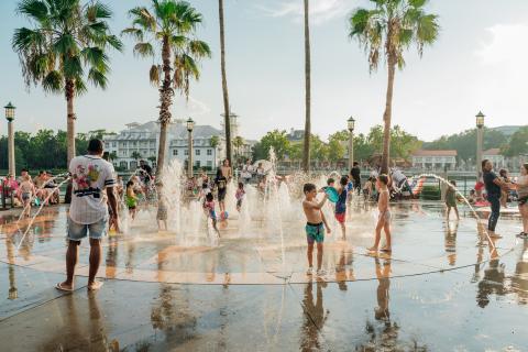 Families and children playing in the splash pad fountains at Celebration Town Center in Kissimmee, Florida.