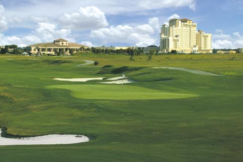Expansive view of the championship golf course and clubhouse at Omni Orlando Resort at ChampionsGate in Kissimmee, Florida, on a sunny day.