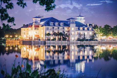 The lights within and around the Inn at Celebration in Celebration, Florida, reflect onto the lake and surrounding trees in the evening.