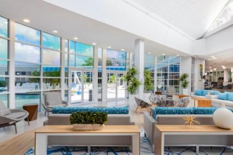 Bright and modern hotel lobby with floor-to-ceiling windows overlooking the pool area at Holiday Inn Resort Kissimmee by the Parks in Kissimmee, Florida.