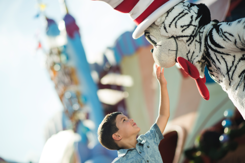 A young boy smiles and reaches up to greet the Cat in the Hat character at Seuss Landing in Universal’s Islands of Adventure.