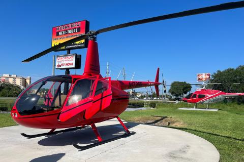 Two red helicopters parked on a sunny day at International Heli-Tours in Kissimmee, Florida, ready for scenic flights over Central Florida.