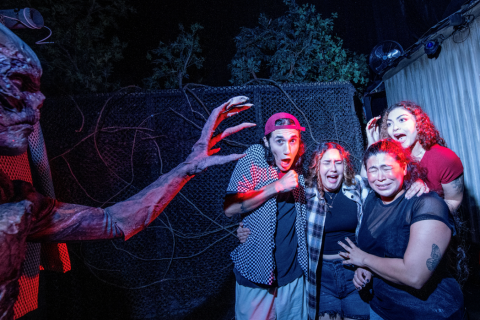 A group of friends screams and laughs as a monster lunges toward them inside a Stranger Things-themed haunted house at Universal Orlando’s Halloween Horror Nights.