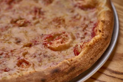 Close-up of a vegan cheese pizza from Flippers Pizzeria in Old Town, featuring a golden, hand-tossed crust and melted vegan cheese over tomato sauce.