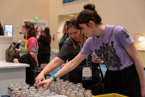 Meeting attendees selecting canned beverages from a refreshment table during a conference break.