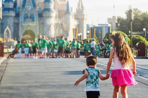 Two young children hold hands while walking down Main Street, U.S.A. toward Cinderella Castle at Walt Disney World, with the castle softly blurred in the background.