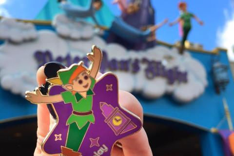 A lady holds a Peter Pan pin outside Peter Pan's Flight