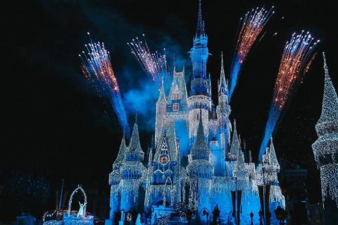 Cinderella Castle lit up at night by projections, lights, and fireworks, during the Frozen Christmas Wish performance. 
