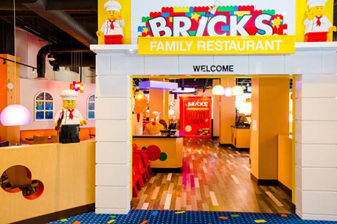 Entrance to Bricks Family Restaurant at LEGOLAND® Florida Resort, featuring colorful LEGO décor, playful lighting, and LEGO chef figures welcoming guests.