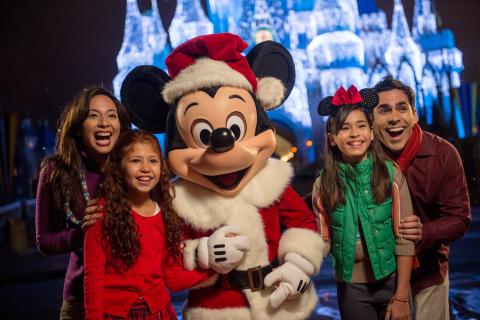 Mickey Mouse poses with guests during the holiday season