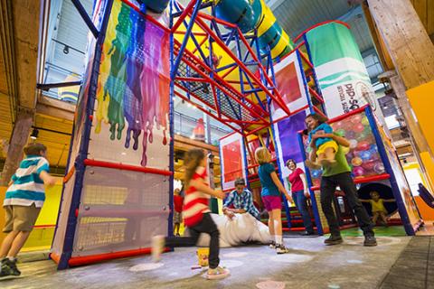 Children and families play inside a colorful indoor climbing structure at Crayola Experience, surrounded by bright artwork and interactive elements.
