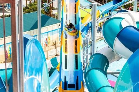Guest riding a bright yellow and blue water slide at Island H2O Water Park in Kissimmee, surrounded by colorful twisting slides and sunny skies.