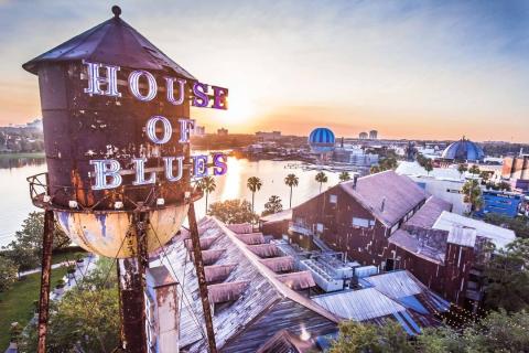 Sunset view of the House of Blues water tower and rustic concert hall at Disney Springs, with Lake Buena Vista, Florida, and surrounding attractions in the background.
