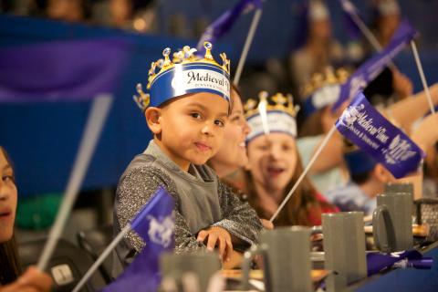 A child wearing a crown eats at Medieval Times 