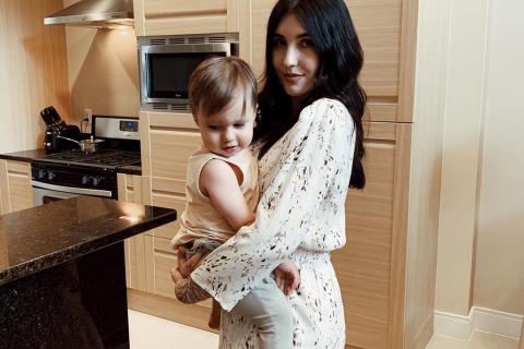 Motherhood and lifestyle influencer @IzzyRose holding her young child inside a Kissimmee, Florida, vacation home kitchen.
